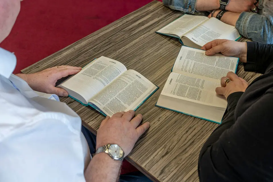 People reading together at a table during a study group.