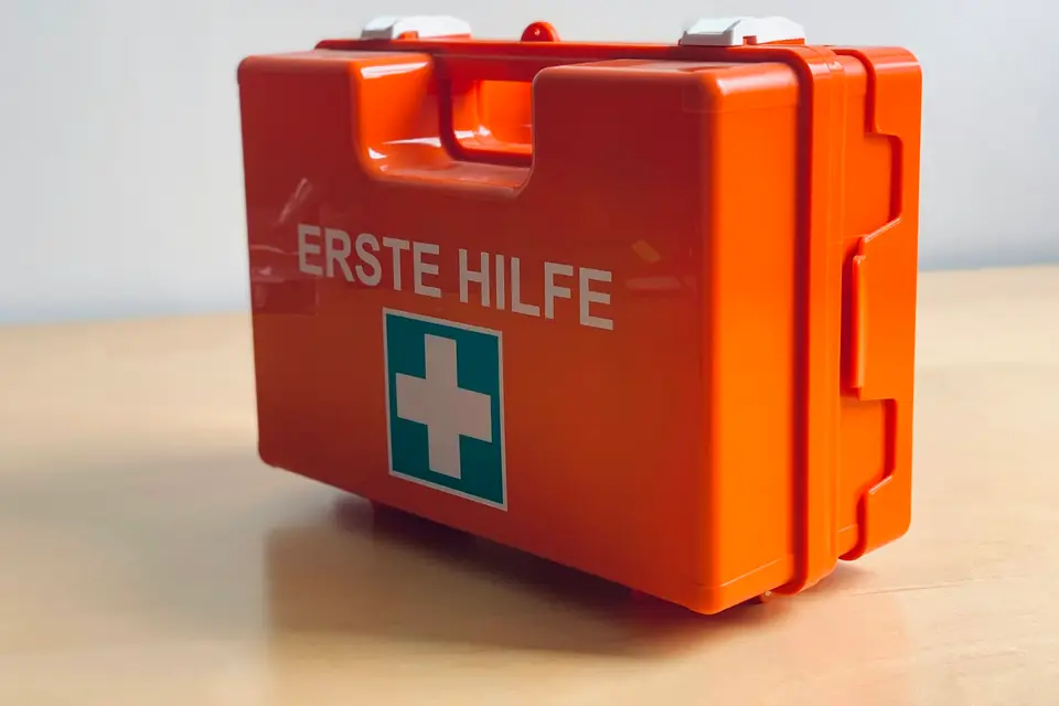 Orangefarbener Erste-Hilfe-Koffer auf einem Holztisch