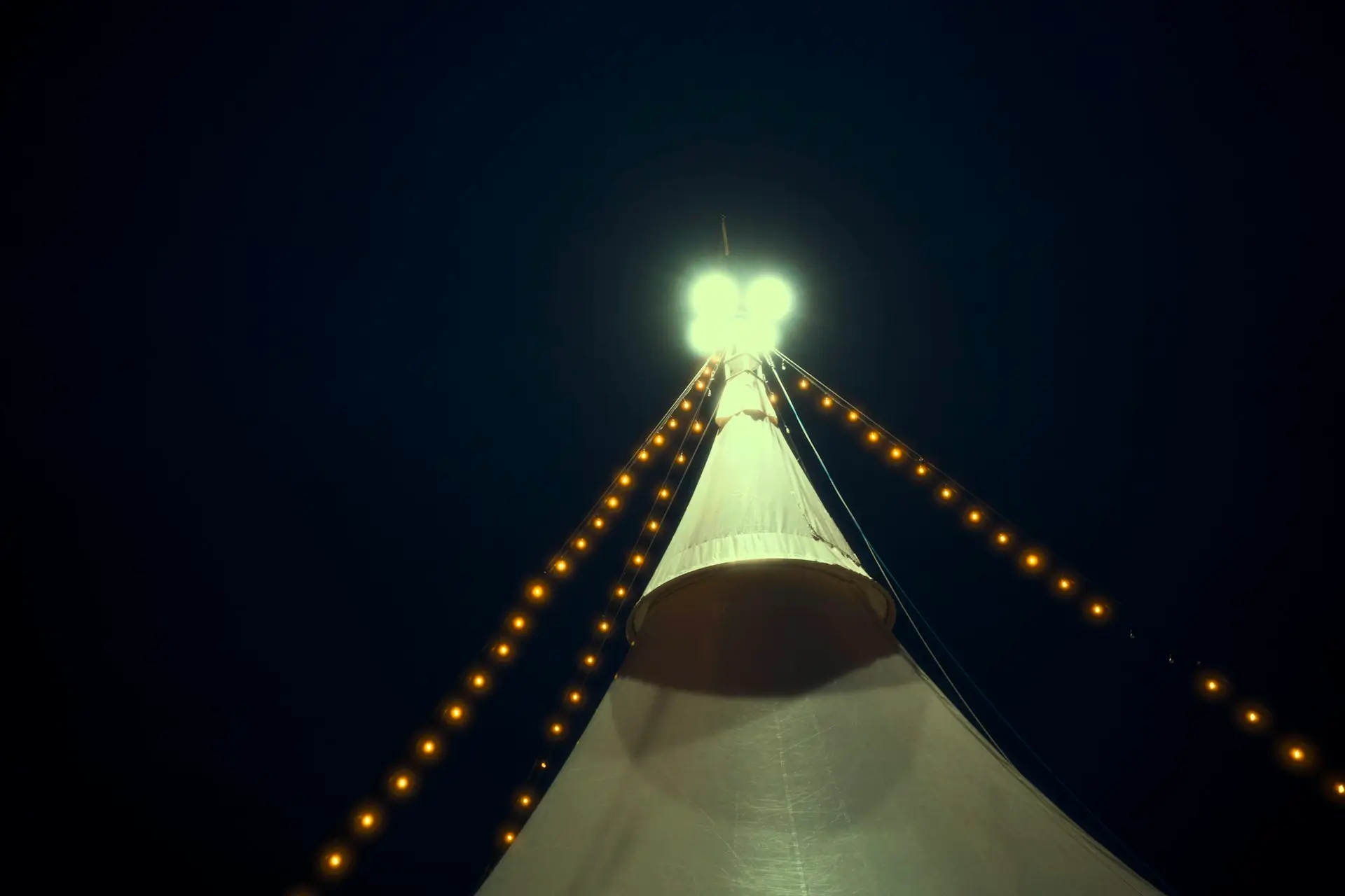 Spitze eines beleuchteten Festzelts bei Nacht