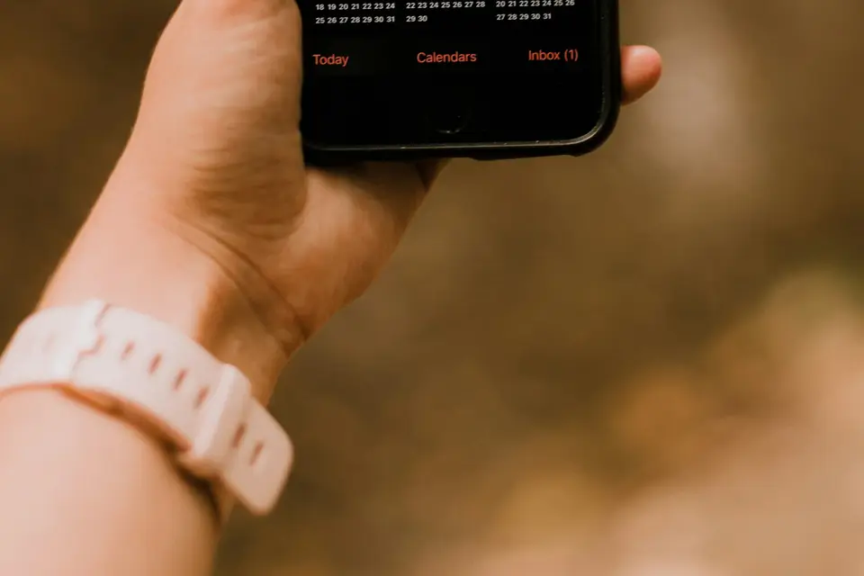Eine Hand hält ein Smartphone mit Terminübersicht