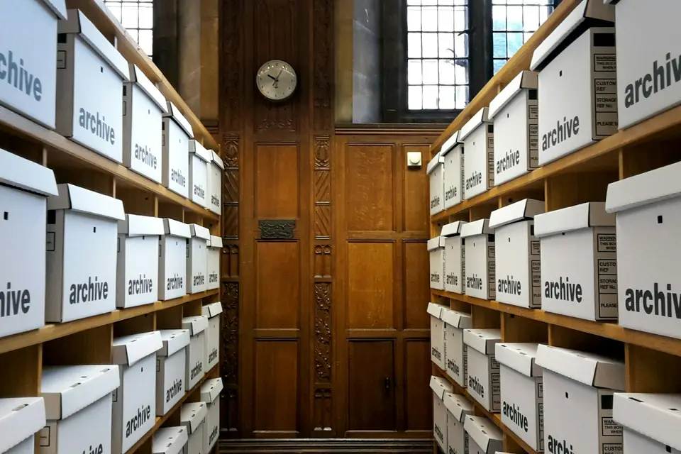 Regale voller beschrifteter Archivkartons in einem holzgetäfelten Raum