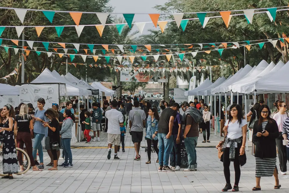 Besucher gehen an einem Festtag zwischen weißen Pavillons unter bunten Wimpelketten entlang