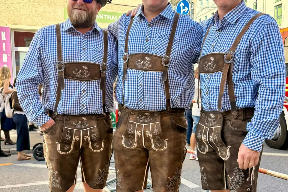 Drei Männer in Lederhosen und karierten Hemden