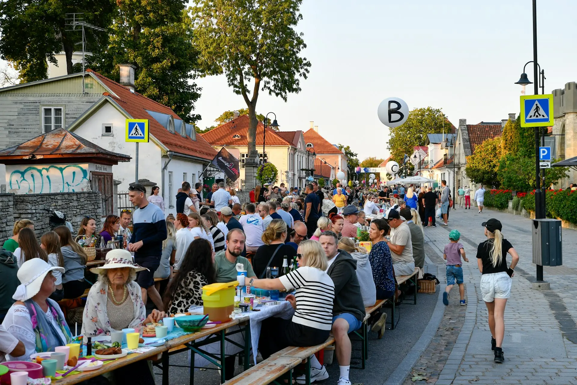 Gäste sitzen bei einem Straßenfest an langen Tischen in einer Altstadtstraße