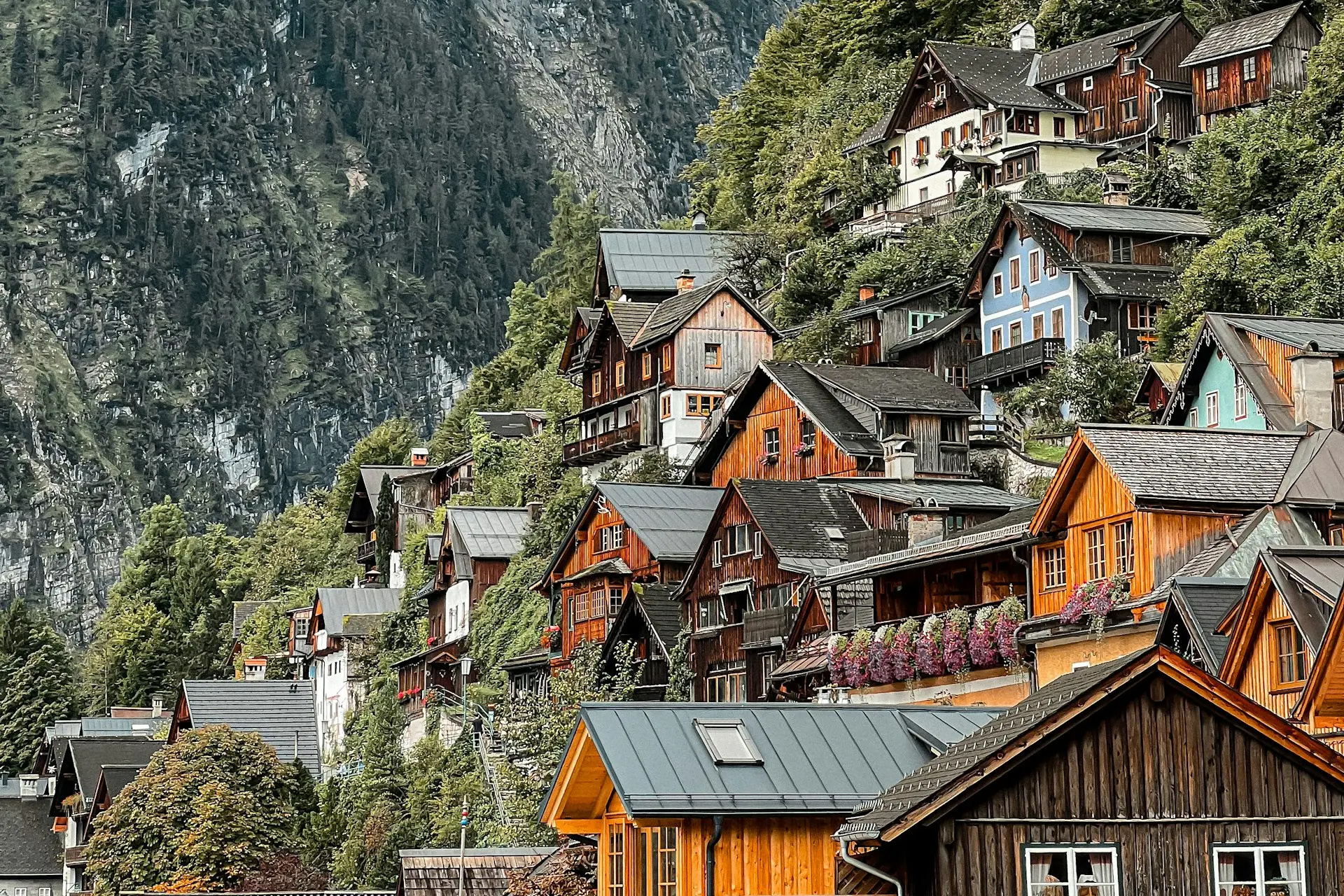 Holzhäuser eines Bergdorfs am steilen Hang vor einer Felswand