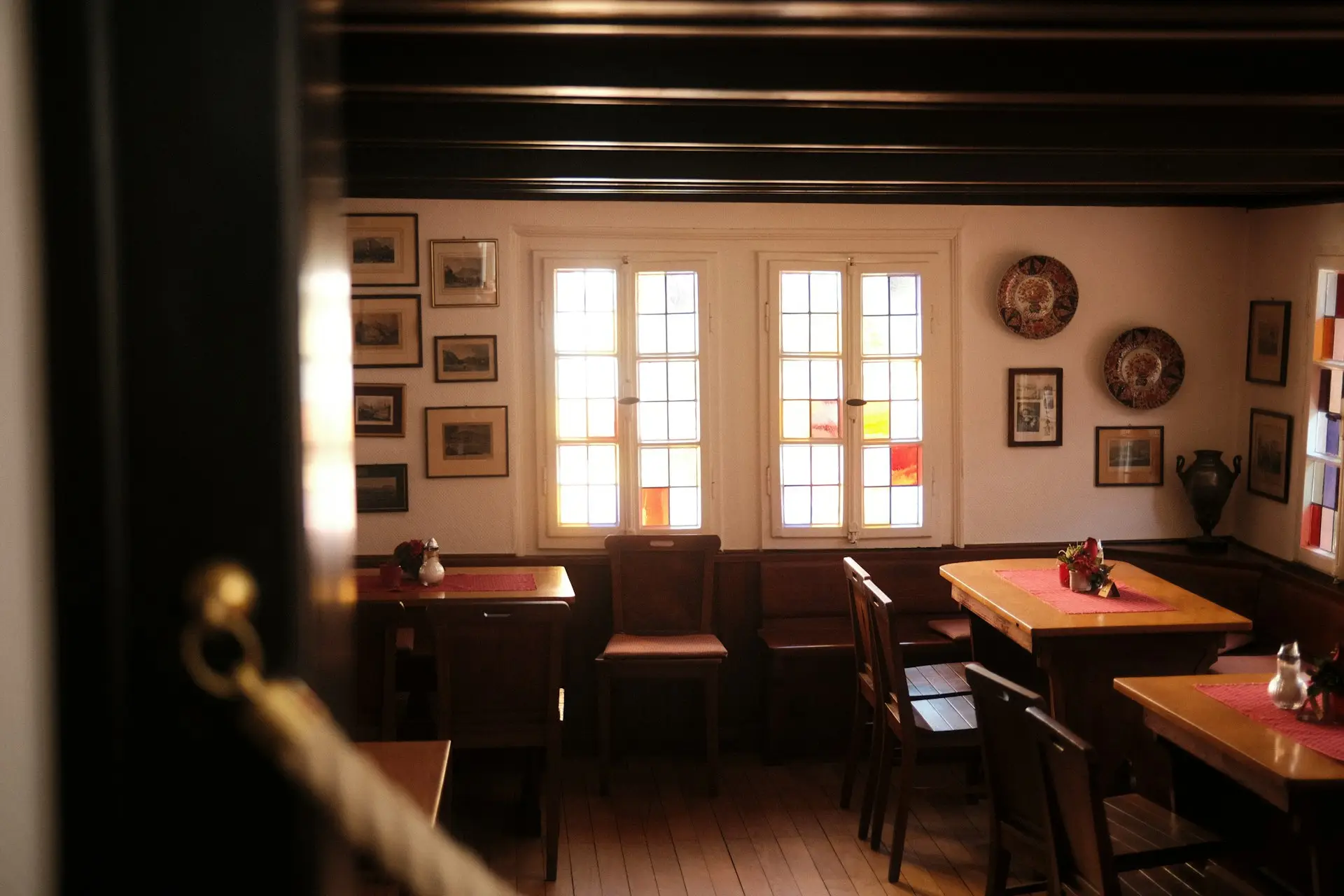 Holztische und Stühle in einem rustikalen Saal mit Buntglasfenstern