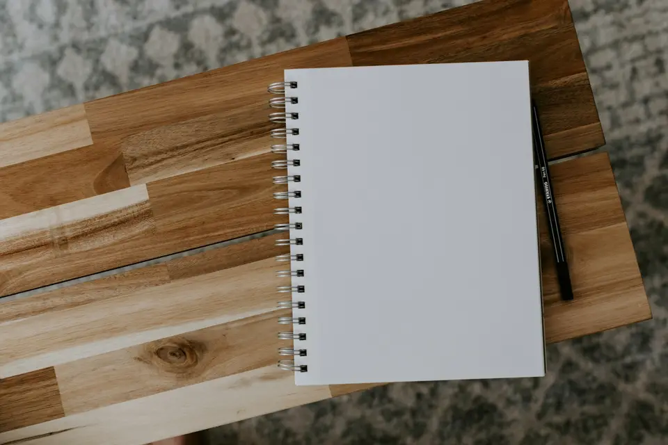 Leerer Spiralblock mit Stift auf einem Holztisch