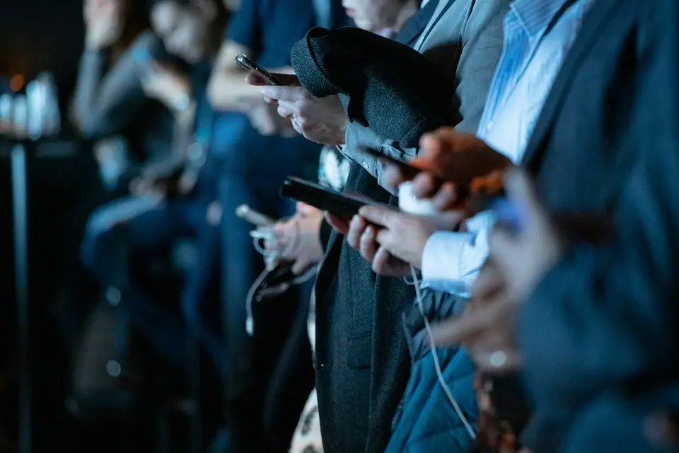 Mehrere Menschen stehen nebeneinander und schauen auf ihre Smartphones