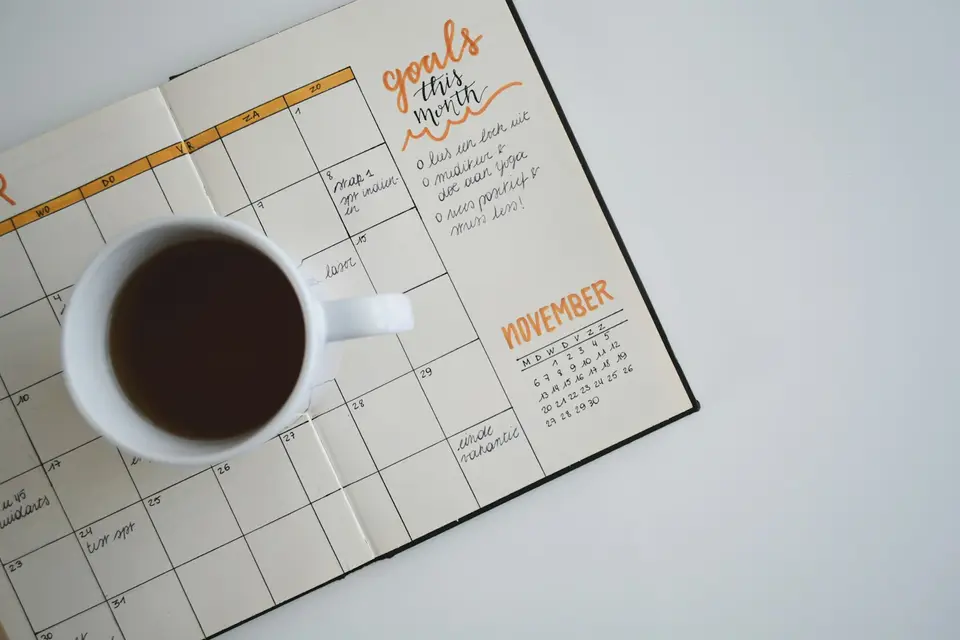 Kaffeetasse auf einem aufgeschlagenen Wochenplaner mit Monatszielen